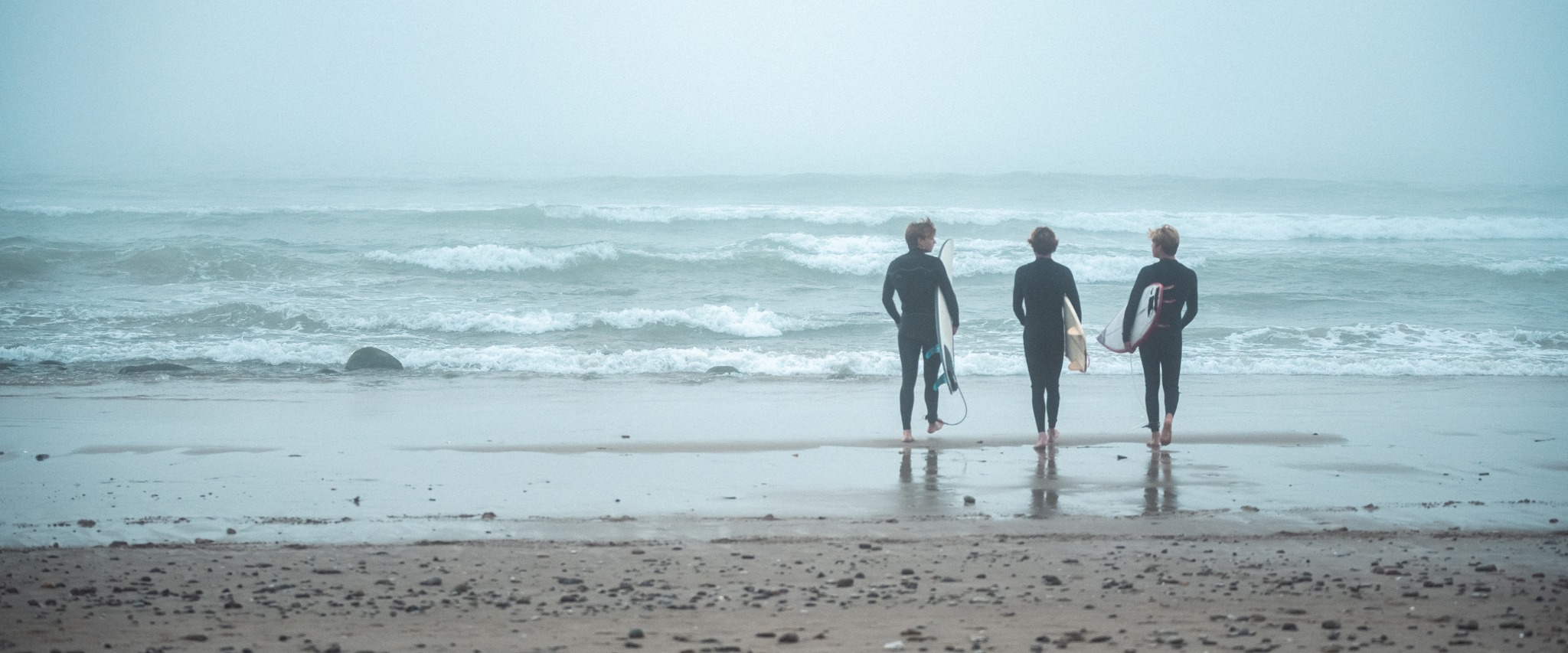 Surfers walking toward the ocean as part of the Njoie lifestyle campaign
